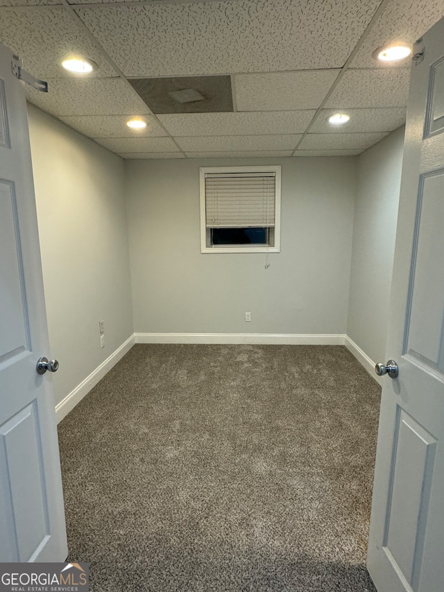 basement featuring a drop ceiling and dark colored carpet