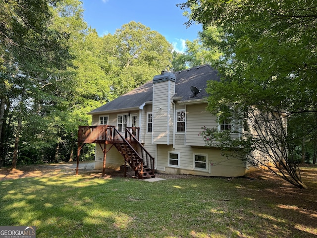 rear view of house with a wooden deck and a lawn