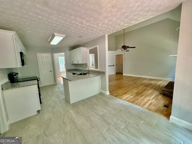 kitchen featuring ceiling fan, light hardwood / wood-style floors, sink, white cabinetry, and vaulted ceiling