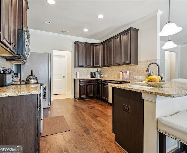 kitchen with pendant lighting, dark hardwood / wood-style floors, dark brown cabinetry, ornamental molding, and light stone countertops