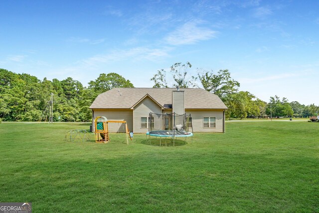 rear view of house featuring a yard and a trampoline