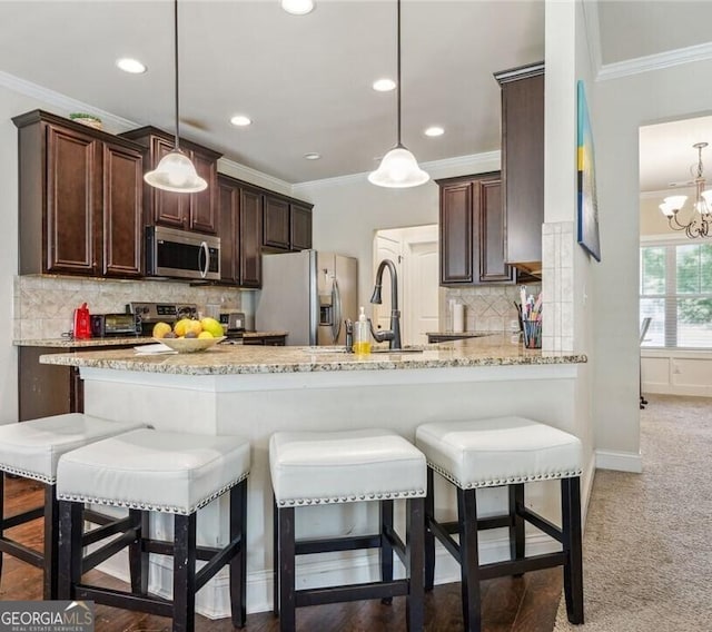 kitchen featuring pendant lighting, crown molding, stainless steel appliances, and kitchen peninsula