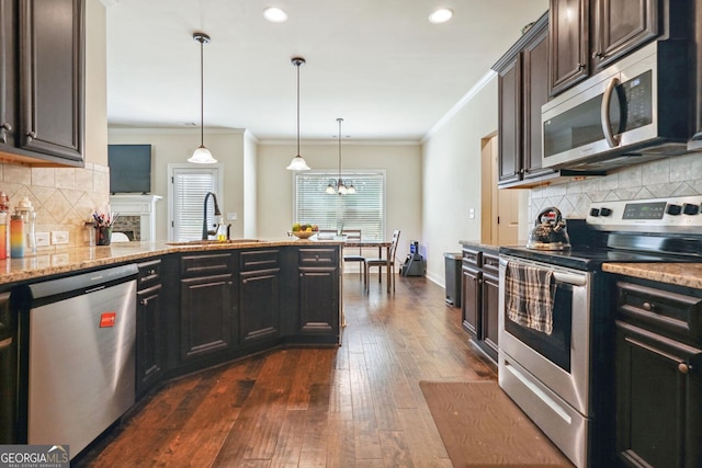 kitchen featuring sink, hanging light fixtures, dark brown cabinets, ornamental molding, and stainless steel appliances