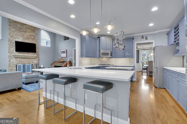 kitchen with a breakfast bar area, sink, stainless steel appliances, and light wood-type flooring