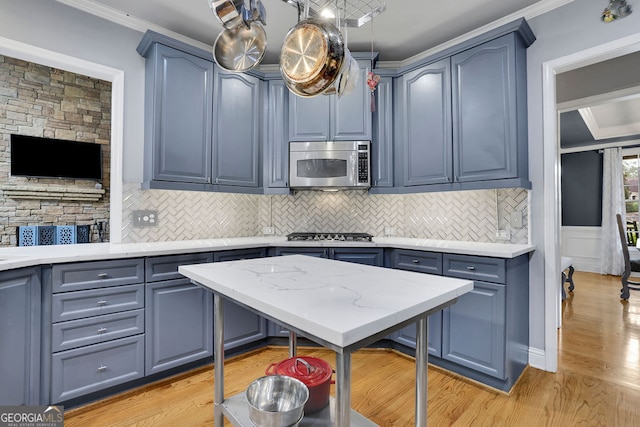 kitchen featuring appliances with stainless steel finishes, light hardwood / wood-style flooring, blue cabinetry, and crown molding