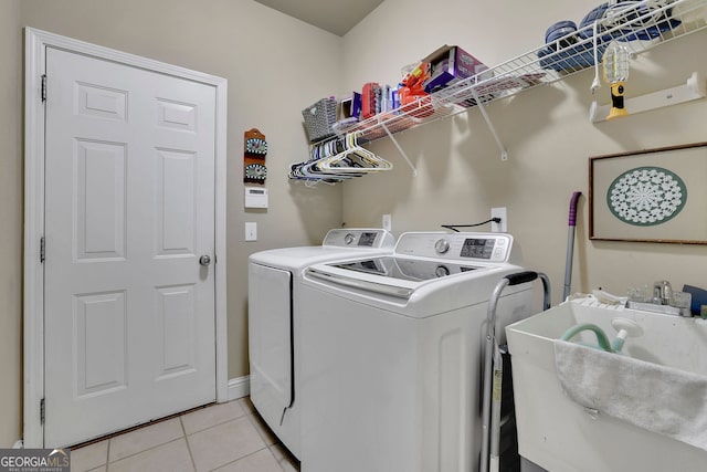 clothes washing area featuring light tile patterned floors, sink, and washer and clothes dryer