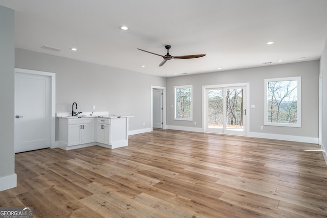 unfurnished living room with ceiling fan, light hardwood / wood-style flooring, and sink