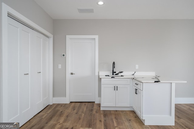 bar with white cabinets, light wood-type flooring, and sink