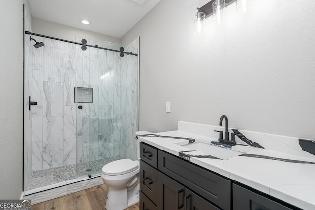 bathroom featuring toilet, vanity, a shower with door, and hardwood / wood-style flooring