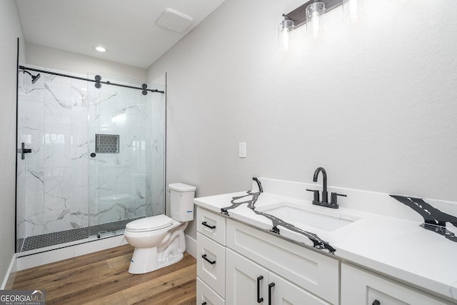 bathroom with an enclosed shower, vanity, toilet, and wood-type flooring