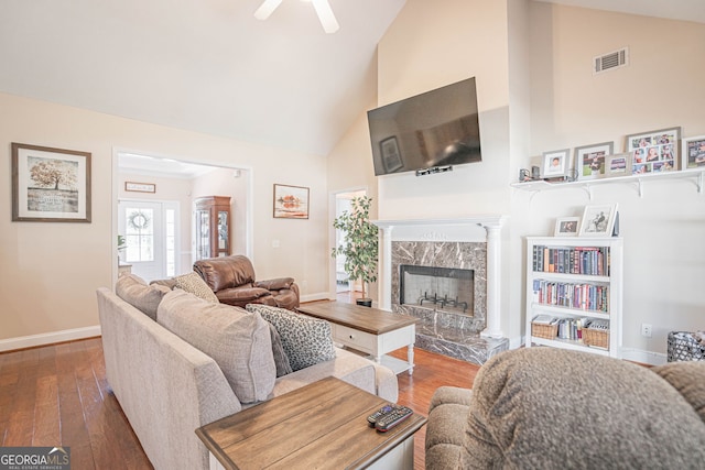 living room with a fireplace, hardwood / wood-style floors, ceiling fan, and high vaulted ceiling