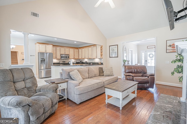 living room featuring decorative columns, high vaulted ceiling, ceiling fan, and hardwood / wood-style flooring