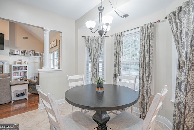 dining area featuring a notable chandelier, lofted ceiling, light hardwood / wood-style flooring, and ornate columns