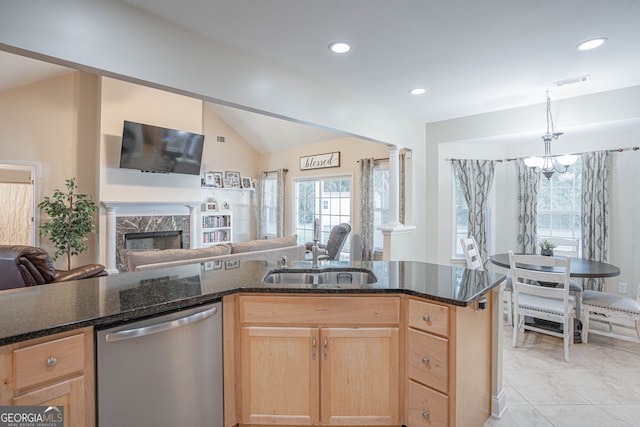 kitchen with sink, a premium fireplace, dishwasher, a notable chandelier, and vaulted ceiling