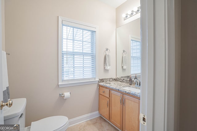 bathroom with a healthy amount of sunlight, vanity, toilet, and tile patterned floors