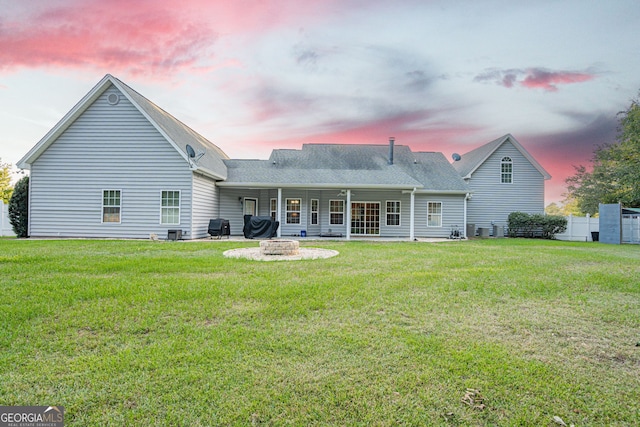 back house at dusk featuring a lawn, a patio area, and an outdoor fire pit