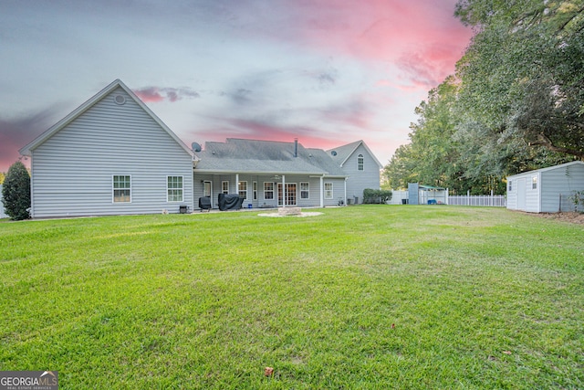 back house at dusk featuring a shed, a yard, and a patio area