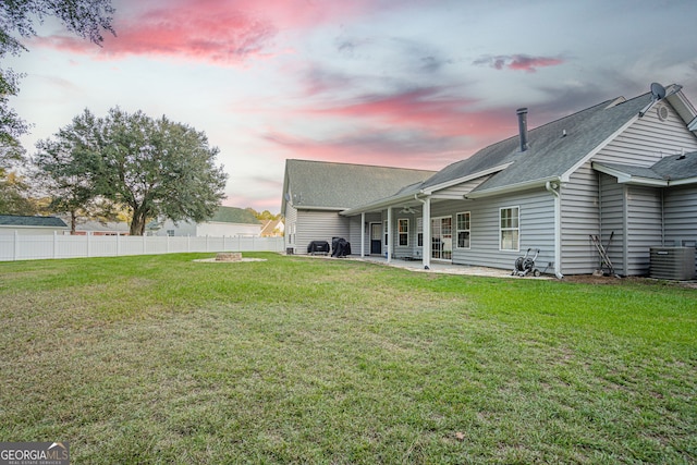 yard at dusk featuring central air condition unit and a patio area