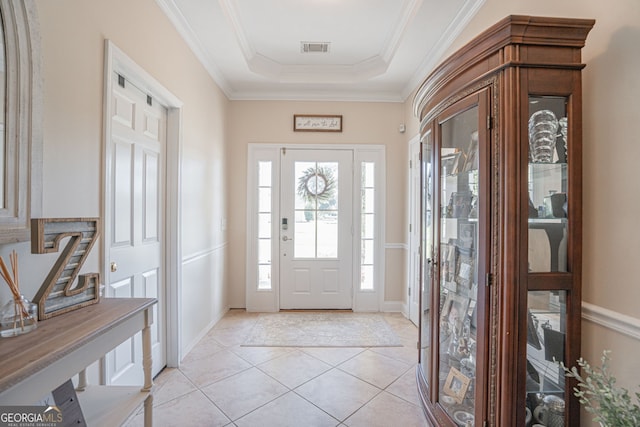 tiled entrance foyer featuring a raised ceiling and crown molding