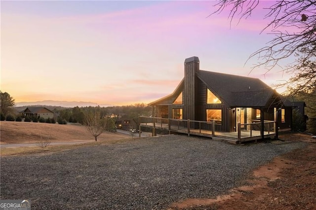 property exterior at dusk featuring a wooden deck