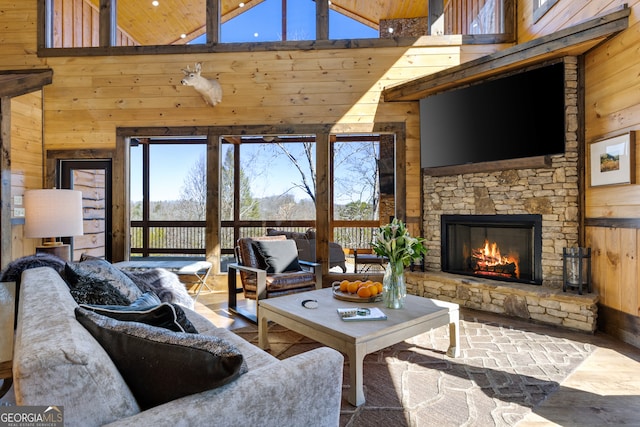 living room featuring wooden walls, a fireplace, and high vaulted ceiling