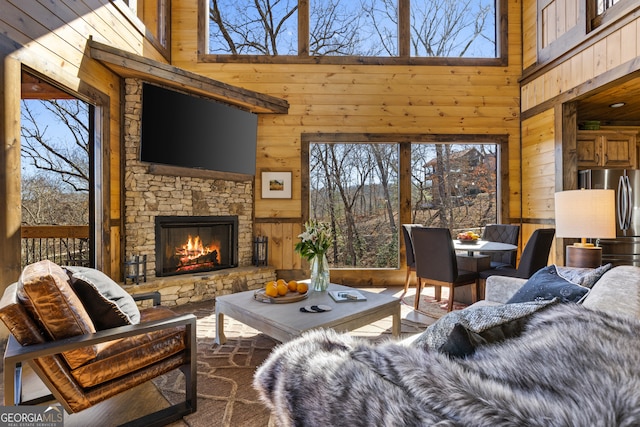 living room featuring a high ceiling, wood walls, and a fireplace