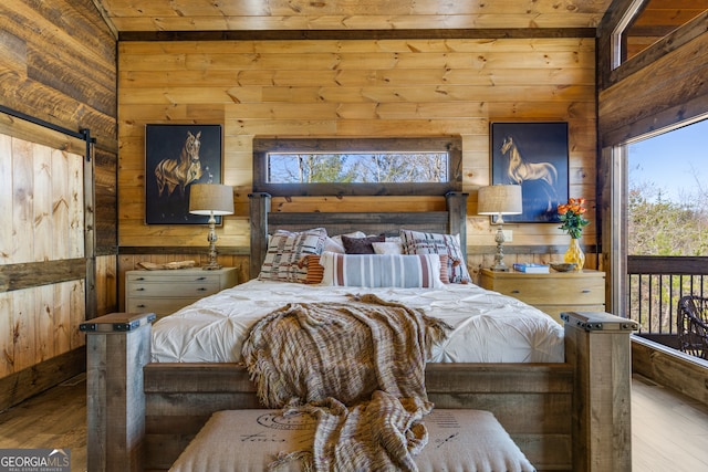 bedroom featuring wooden ceiling, light hardwood / wood-style floors, wooden walls, and a barn door