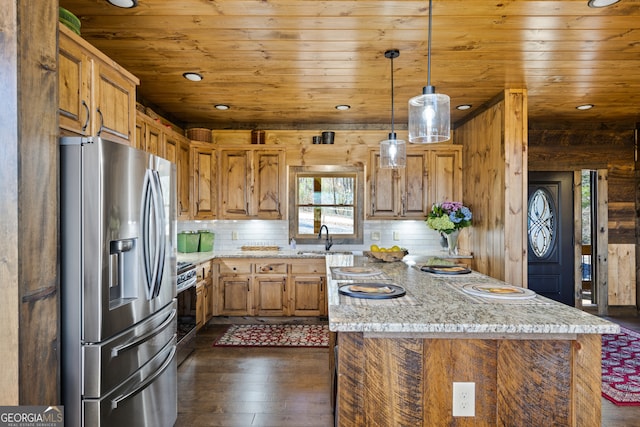 kitchen featuring hanging light fixtures, light stone countertops, stainless steel appliances, a center island, and dark hardwood / wood-style floors