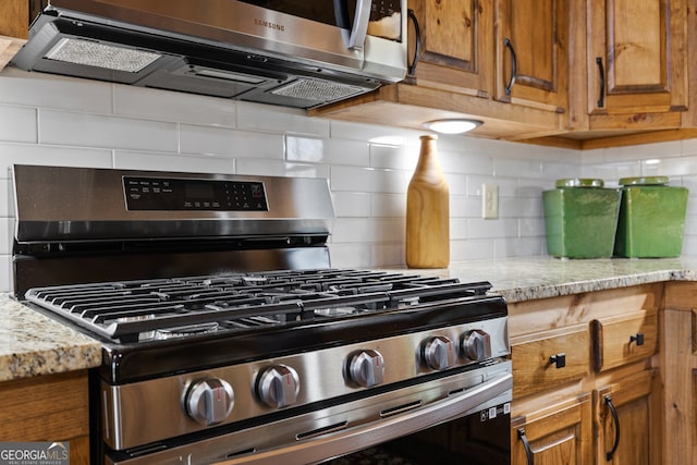 kitchen with light stone counters, appliances with stainless steel finishes, and backsplash