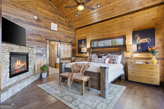 bedroom featuring high vaulted ceiling, wood walls, dark hardwood / wood-style floors, and a barn door