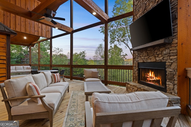 exterior space with ceiling fan, a stone fireplace, and lofted ceiling with beams