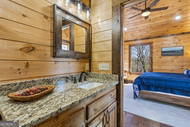 bathroom with ceiling fan, vanity, wooden walls, and hardwood / wood-style flooring