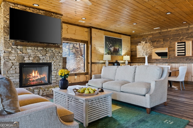 living room featuring wood ceiling, a stone fireplace, wood walls, and dark hardwood / wood-style floors