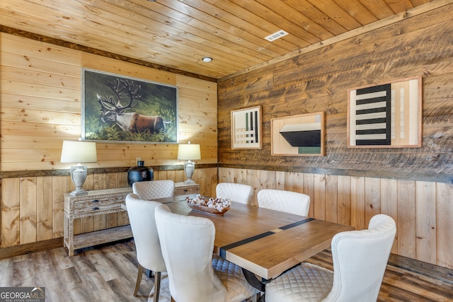 dining room featuring wooden walls, hardwood / wood-style floors, and wood ceiling