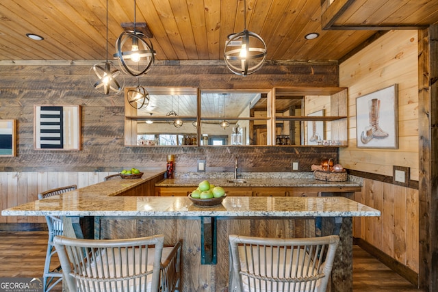 kitchen with wooden walls, dark hardwood / wood-style floors, and decorative light fixtures