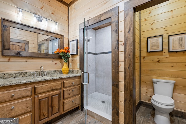 bathroom featuring vanity, wood-type flooring, wooden walls, walk in shower, and toilet