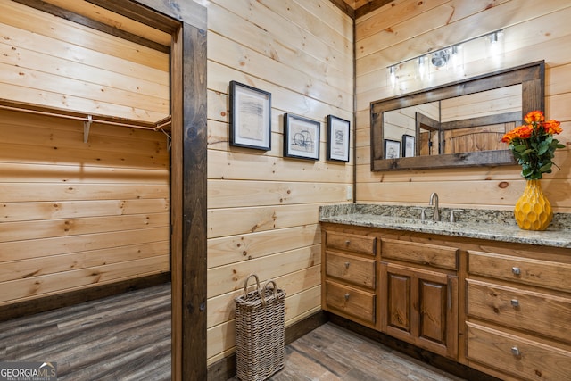 bathroom featuring vanity, wooden walls, and hardwood / wood-style flooring