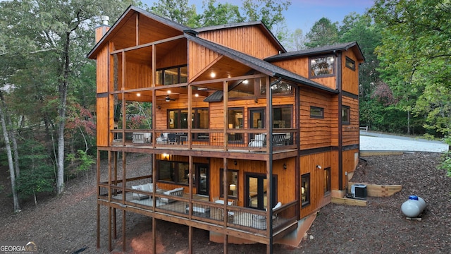 back house at dusk with a balcony and central AC