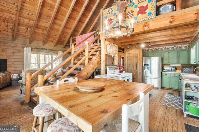 dining room featuring wood ceiling, light wood-type flooring, vaulted ceiling with beams, wooden walls, and sink