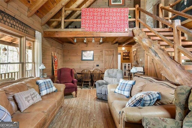 living room featuring vaulted ceiling with beams, wood-type flooring, wood walls, and track lighting