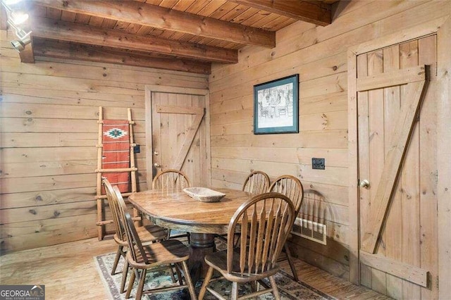 dining area with light hardwood / wood-style flooring, beam ceiling, wood walls, and wooden ceiling