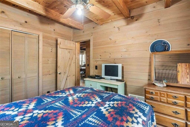 unfurnished bedroom featuring ceiling fan, beamed ceiling, wood walls, a closet, and wooden ceiling