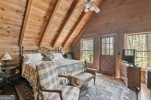 bedroom with lofted ceiling with beams, wood-type flooring, multiple windows, and wooden walls