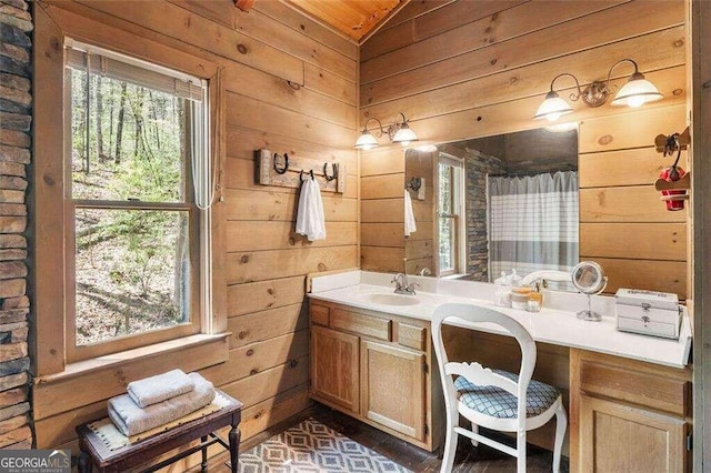 bathroom with vanity, wooden walls, and lofted ceiling