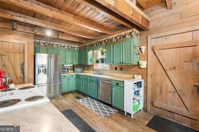 kitchen featuring light hardwood / wood-style floors, wooden walls, appliances with stainless steel finishes, and green cabinets