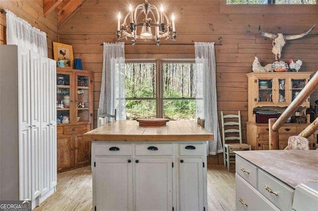 kitchen with light hardwood / wood-style floors, a center island, white cabinets, vaulted ceiling, and decorative light fixtures