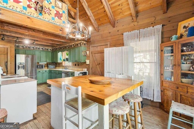 kitchen with appliances with stainless steel finishes, light hardwood / wood-style floors, a chandelier, wooden walls, and green cabinets