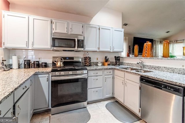 kitchen featuring appliances with stainless steel finishes, light stone countertops, sink, and white cabinets