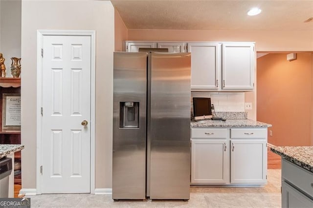 kitchen with light stone countertops, stainless steel refrigerator with ice dispenser, light tile patterned floors, and tasteful backsplash