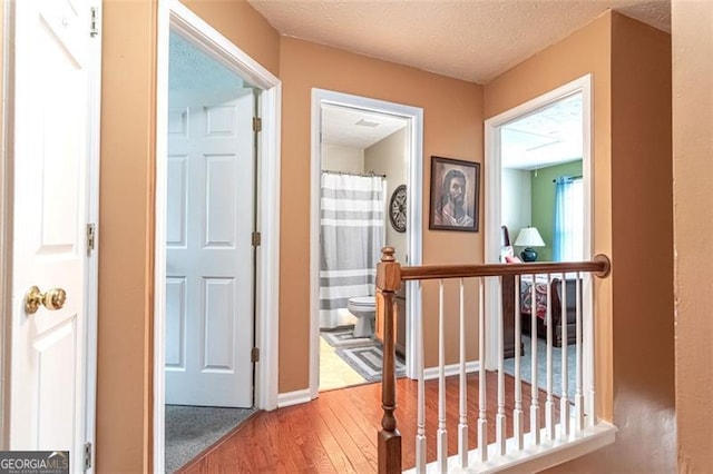 corridor featuring a textured ceiling and hardwood / wood-style floors